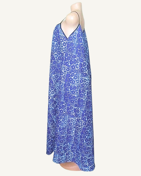 Robe longue batik bleu roi et bleu ciel, motifs circulaires africains denses, bretelles fines liseré noir, encolure V, coupe trapèze très ample, ourlet asymétrique longueur cheville · exemplaire unique Giwax Boutique.
