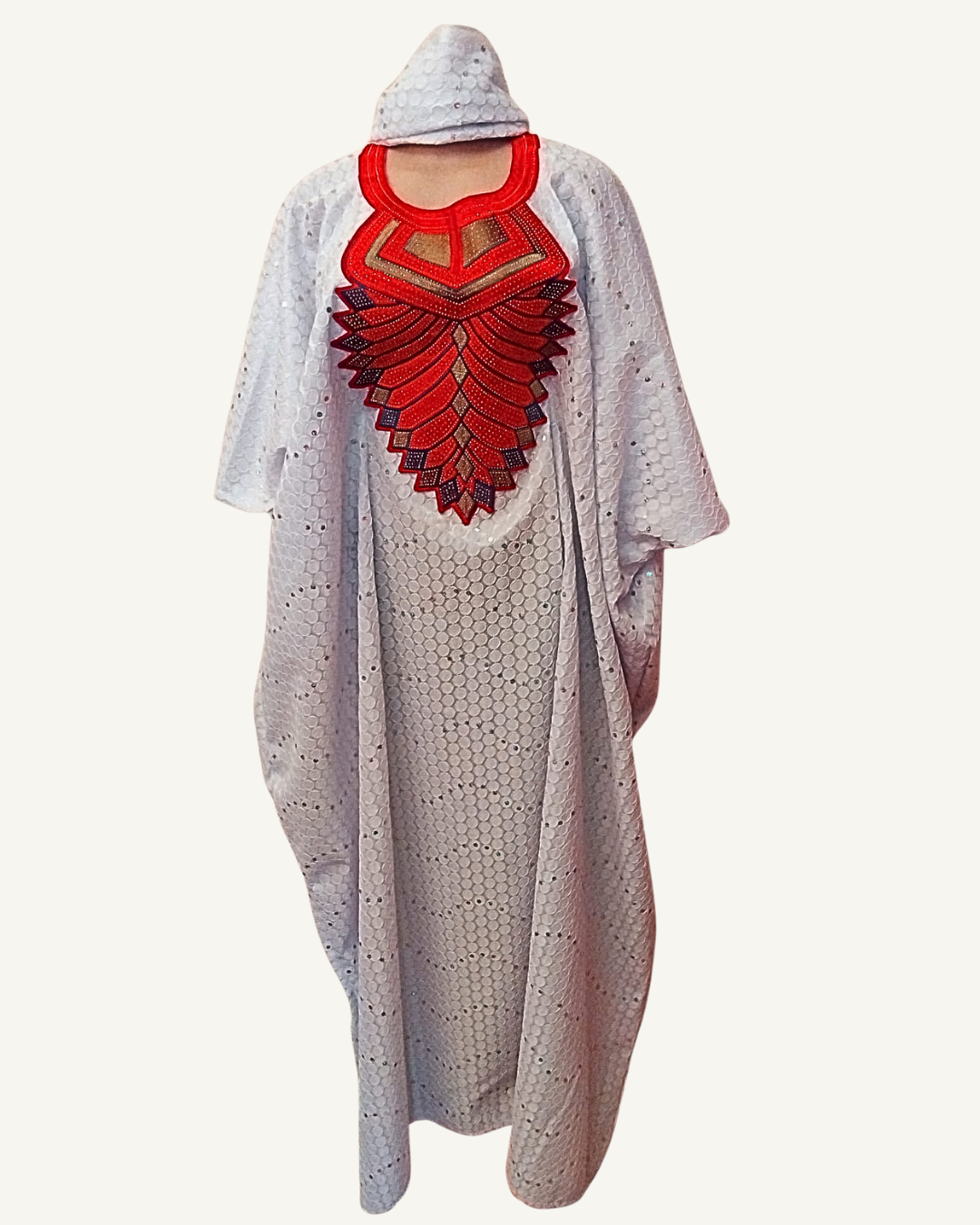 Ensemble boubou long blanc nacré, grand plastron brodé rouge écarlate bordeaux et or en forme de soleil déployé, col arrondi rouge structuré, sequins argent ton sur ton sur tissu nids d'abeille, coupe caftan ample longueur cheville, foulard assorti noué en tête.