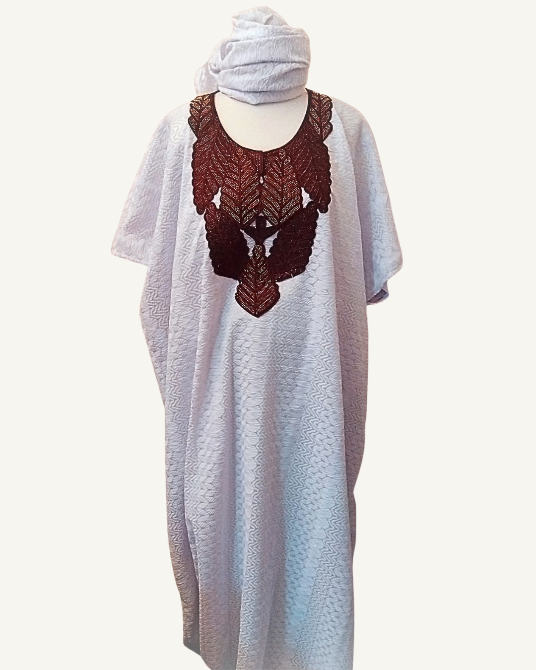 Ensemble boubou long en brocart africain blanc à motifs jacquard en relief, plastron brodé marron profond en forme d'oiseau symétrique aux feuilles nervurées, col arrondi, manches courtes larges, coupe caftan ample longueur cheville, foulard assorti drapé en tête.