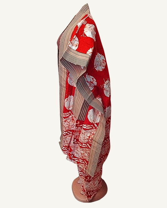Vue de profil — silhouette de l'ensemble kimono ouvert sur le pantalon coordonné, tombé des manches larges, bordure rayée beige visible sur l'ourlet et la cheville du pantalon, tissu batik rouge à cercles blancs.