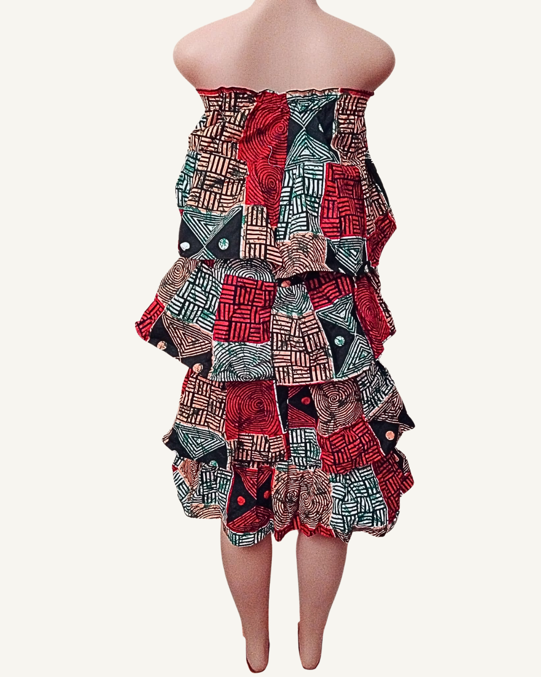 Vue dos — robe bustier wax à volants étagés, bande smockée visible en haut du dos, cascade de quatre rangs de volants, même composition graphique multicolore rouge noir vert.