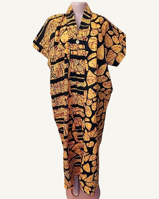 Robe longue batik africain fond noir, grandes formes organiques dorées aux nervures rouge sang couvrant toute la surface, motif secondaire de bandes hachurées côté gauche, col châle croisé V profond boutonné, manches courtes tombantes, fente basse devant, longueur cheville.