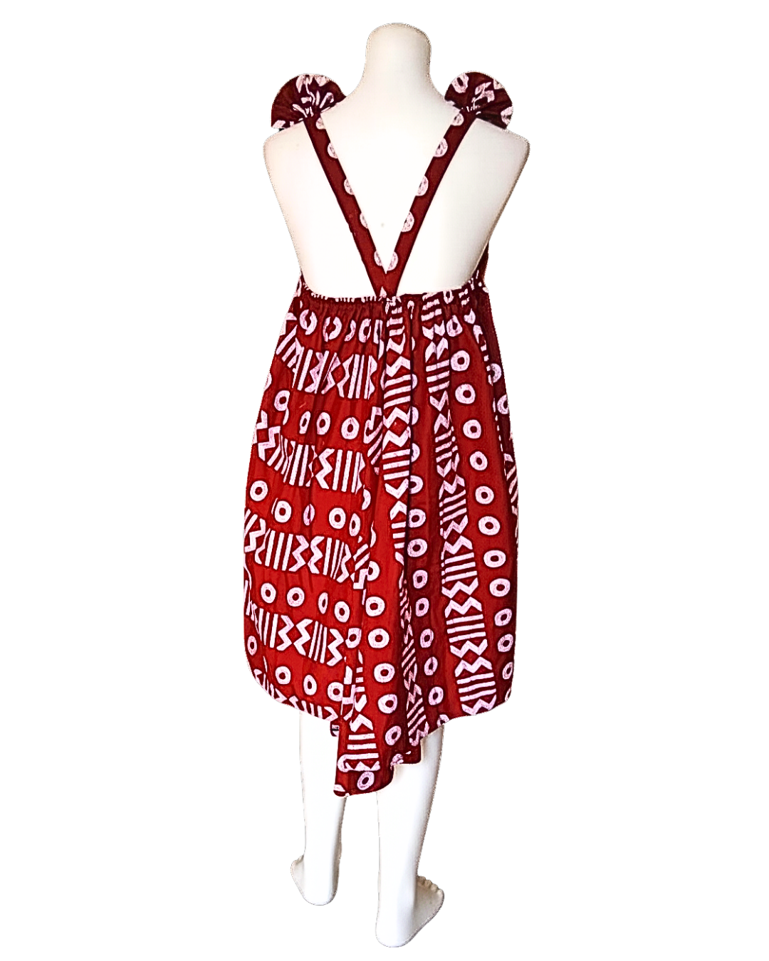 Dos nu ouvert en V d'une robe batik bordeaux, bretelles croisées nouées aux épaules, coupe évasée et ourlet asymétrique.