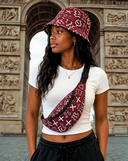 Femme portant un bob batik bordeaux à motifs bogolan blancs et un sac banane assorti en bandoulière, devant l'Arc de Triomphe · Giwax Boutique.