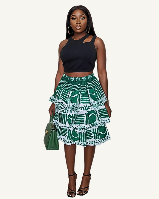 Jupe volants étagés imprimé africain vert et blanc portée · trois rangs de volants froncés · taille élastiquée · longueur genou · top noir exemple de style · couleur du crop top varie selon stock disponible.