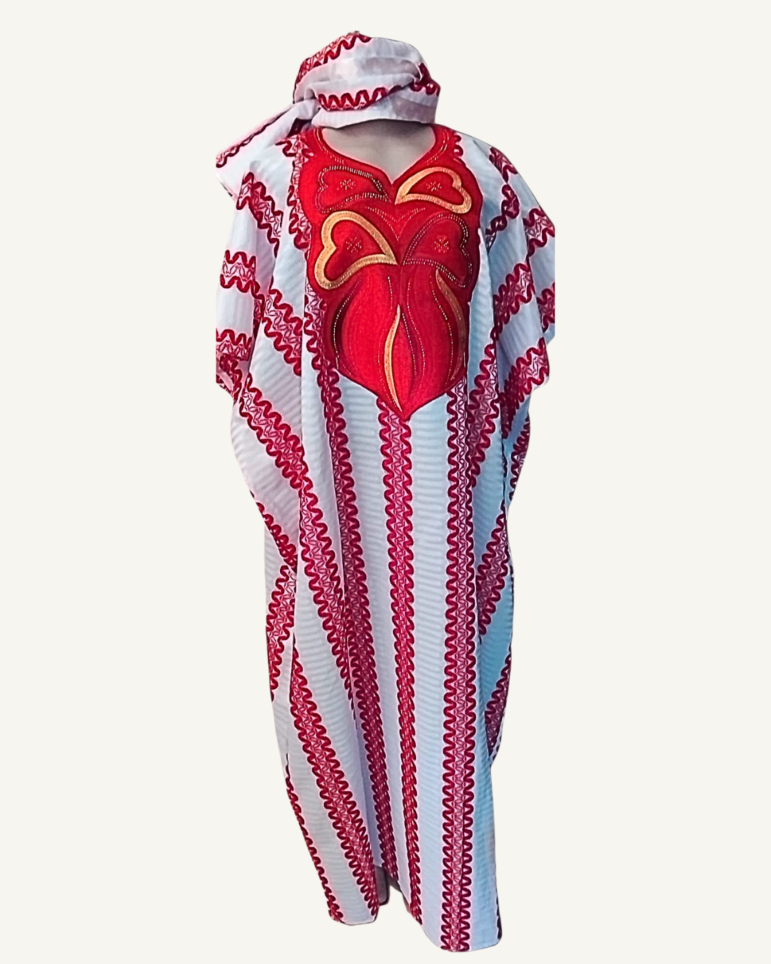 Ensemble boubou long blanc à micro-rayures, larges bandes verticales brodées rouge framboise festonné de l'épaule à l'ourlet, grand plastron central papillon stylisé en appliqué brodé rouge vif et or, col en cœur, manches courtes larges, coupe caftan ample longueur cheville, foulard assorti bordé rouge noué en tête.