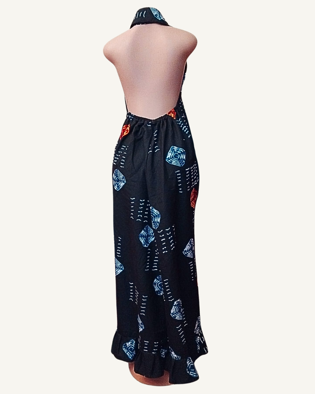 Vue dos — robe adire noir dos entièrement nu, attache halter nouée à la nuque, froncé élastiqué bas du dos, losanges bleu et rouge visibles, tombé maxi jusqu'à la cheville avec volant d'ourlet.