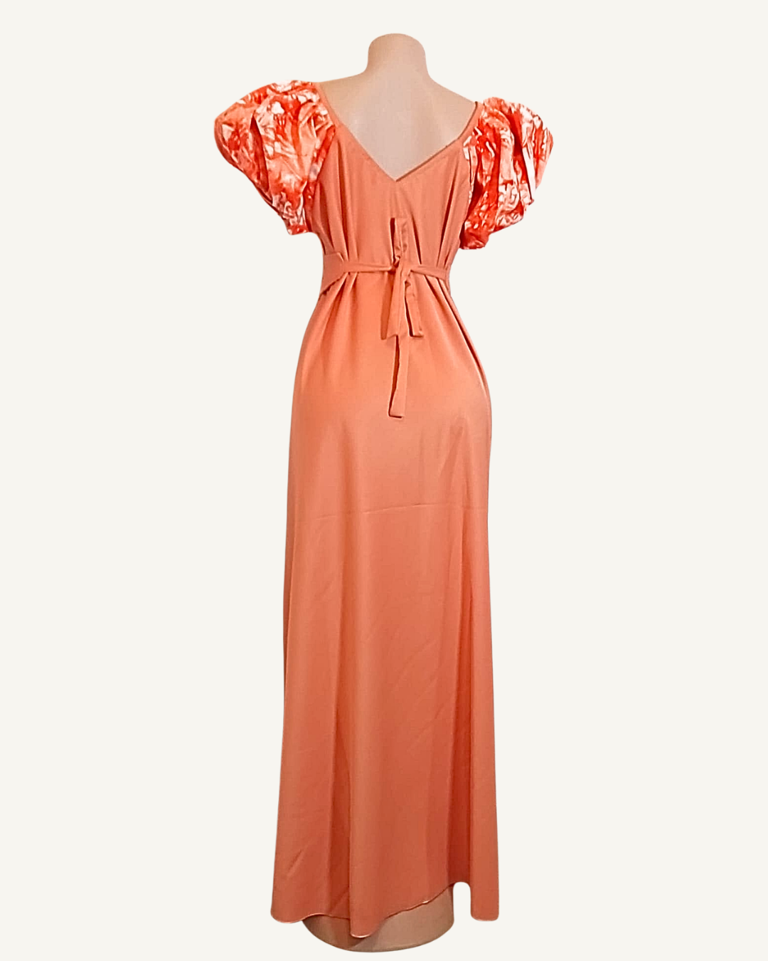 Dos d'une robe longue corail, manches bouffantes wax orange, ceinture du corset amovible nouée dans le dos, coupe très ample et fluide longueur cheville.