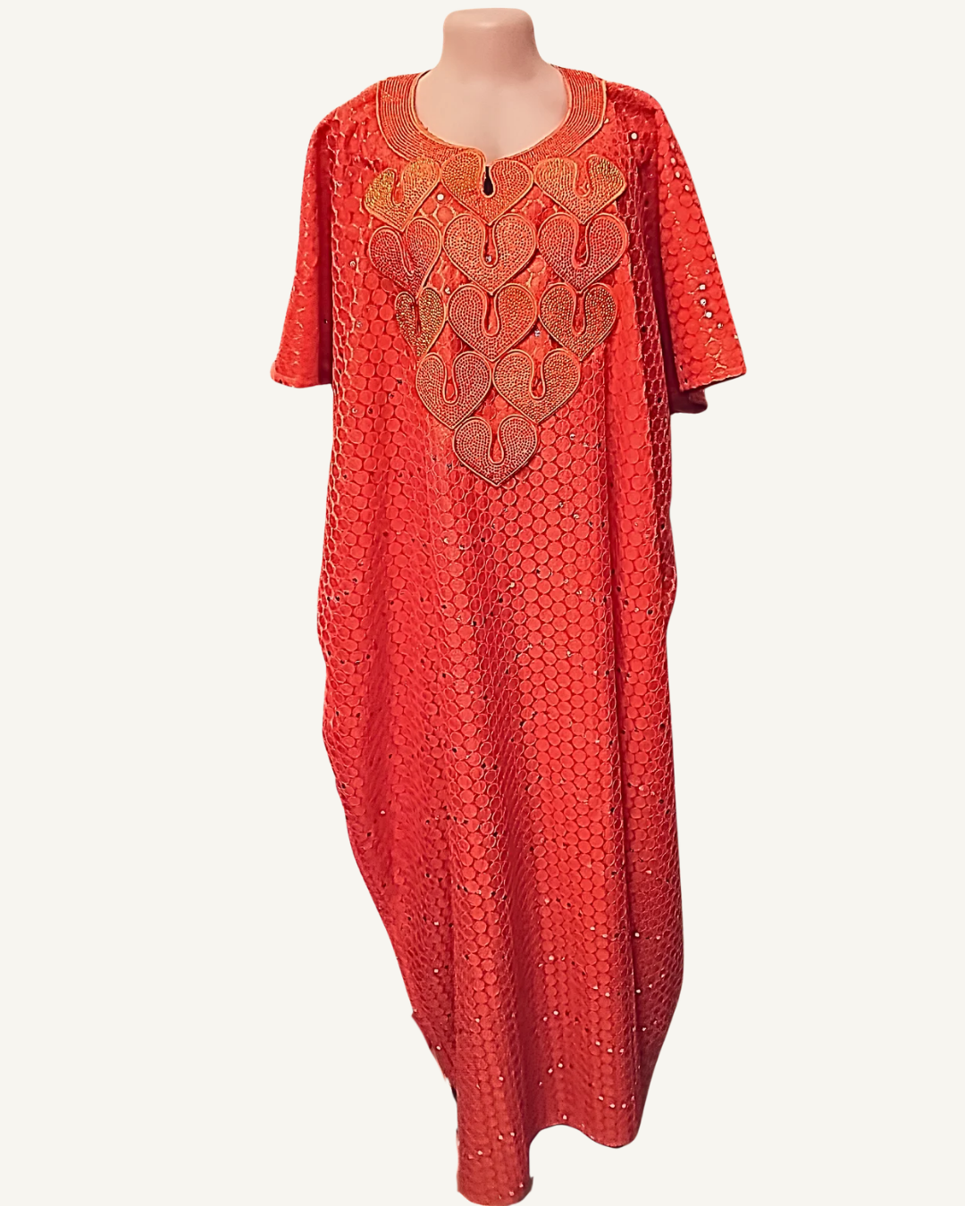 Boubou long rouge corail à motifs nids d'abeille relief avec sequins et strass ton sur ton, grand plastron brodé de cinq cœurs imbriqués en fils or cuivré et champagne avec volutes, col arrondi liseré doré avec zip central, manches courtes droites, coupe caftan ample longueur chevilles.
