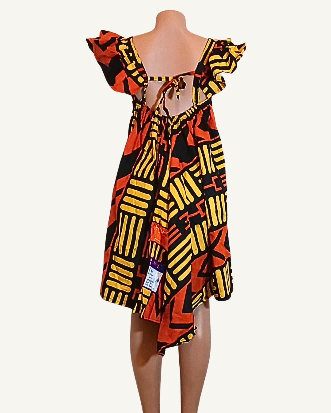 Dos partiellement ouvert avec laçage noué d'une robe wax motifs africains noir et jaune, col bardot volanté, coupe ample · exemplaire unique Giwax Boutique.
