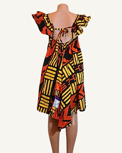 Dos partiellement ouvert avec laçage noué d'une robe wax motifs africains noir et jaune, col bardot volanté, coupe ample · exemplaire unique Giwax Boutique.