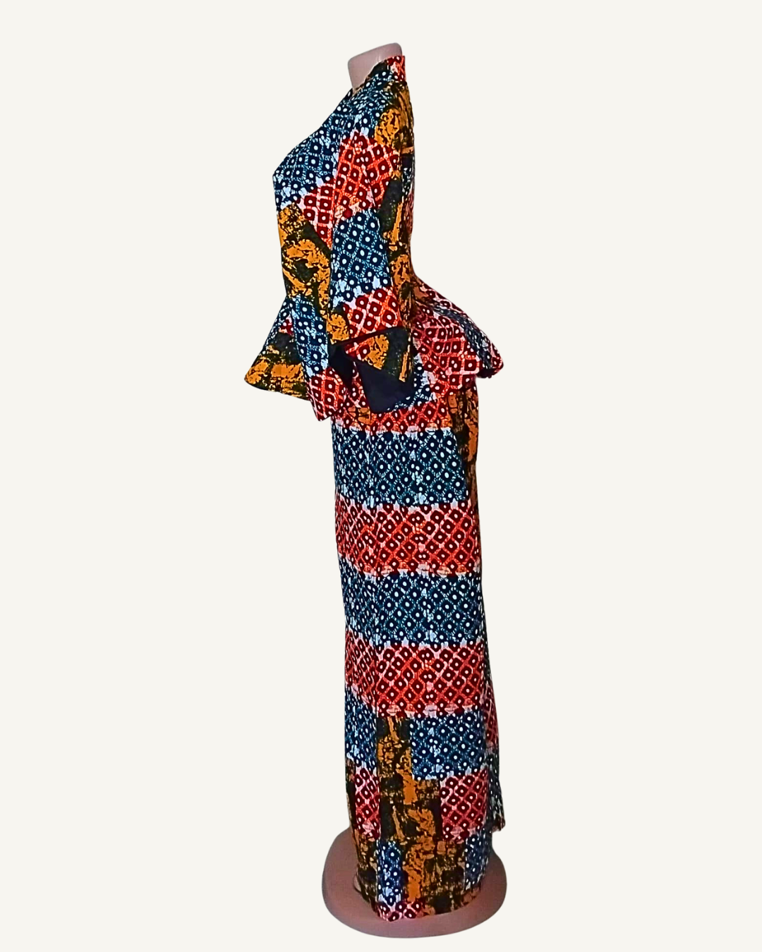 Vue de profil · peplum structuré évasé bien visible · pantalon · fente dos · tombé fluide longueur cheville · wax patchwork multicolore.