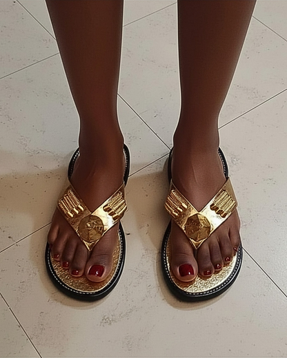 Agbodje dorées traditionnelles ivoiriennes portées · bride en V métallisée or · médaillon central doré · semelle gaufrée or · contour noir · vue de dessus.