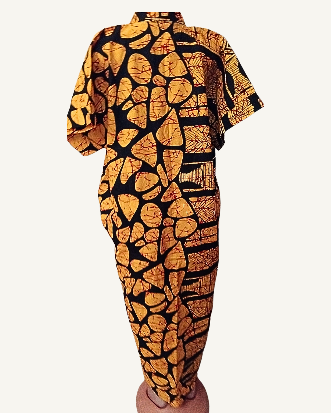 Vue dos — robe batik africain or et noir, composition uniforme de galets dorés sur fond noir, coupe droite légèrement évasée, tombé jusqu'à la cheville, manches courtes visibles.
