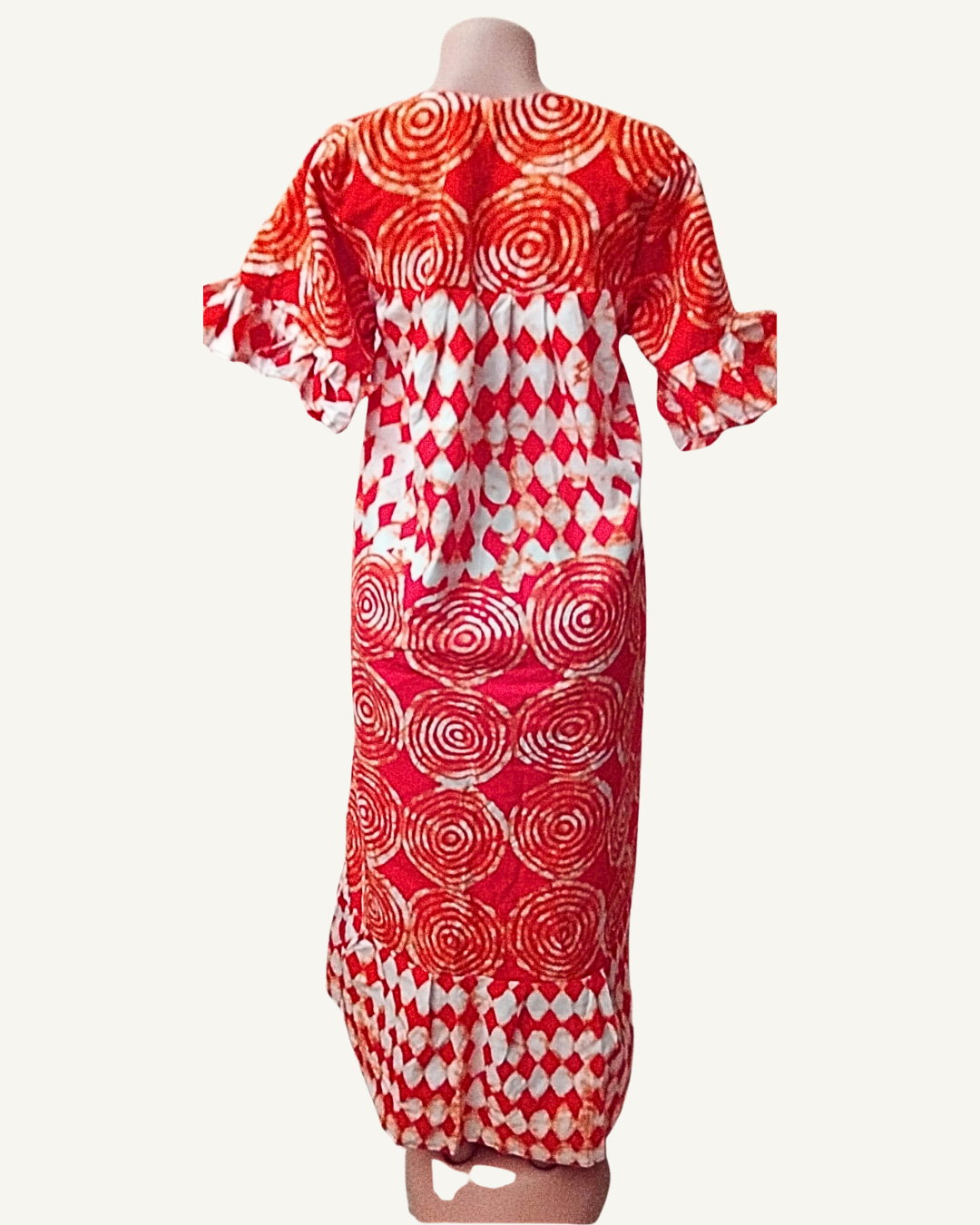Vue dos — robe batik africain rouge, motifs spirales dominant le haut du dos, damier de losanges au milieu et en bordure basse, manches volantées symétriques.