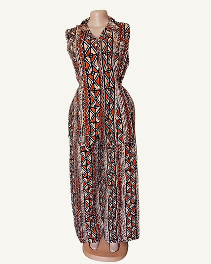 Vue face · blazer wax terracotta sans manches · col retourné · boutonnage devant · taille cintrée · pans asymétriques · motifs géométriques en bandes verticales · pantalon palazzo même tissu.