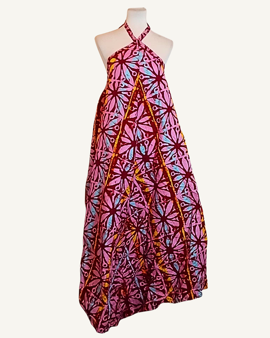 Robe longue batik rose vif à motifs étoilés en rosaces bordeaux et doré, bretelles croisées devant, col halter noué, coupe très ample, ourlet asymétrique longueur cheville · exemplaire unique Giwax Boutique.