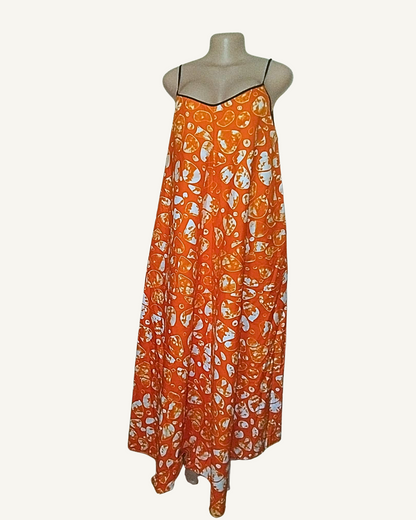 Robe longue batik orange, profil montrant la coupe trapèze généreuse et le tombé fluide jusqu'à la cheville · imprimé africain motifs en bulles.