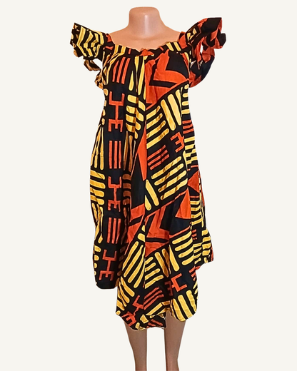 Robe wax à motifs géométriques africains noir, jaune vif et orange, large col bardot volanté froncé tombant sur les épaules, coupe trapèze ample, ourlet asymétrique mi-genou · exemplaire unique Giwax Boutique.