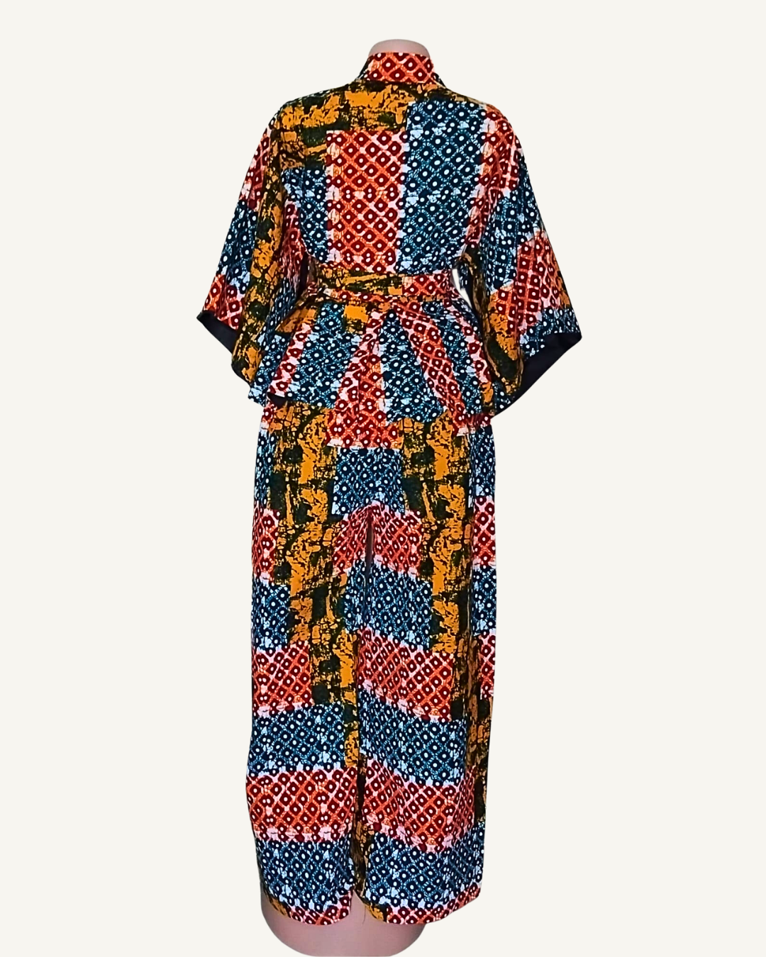 Vue dos · ensemble wax africain patchwork bleu rouge et ocre · top peplum évasé ceinturé · manches courtes · pantalon · longueur cheville · blocs de motifs distincts pois losanges et batik.
