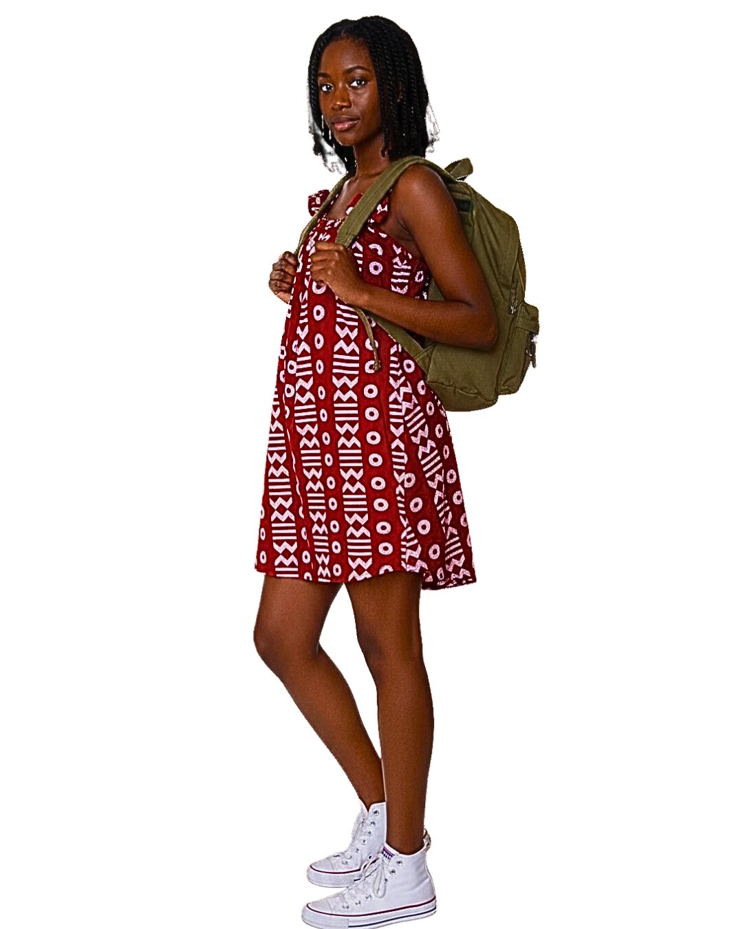 Femme portant une robe batik bordeaux à motifs blancs, dos tourné trois quarts, avec un sac à dos kaki et des sneakers blanches.