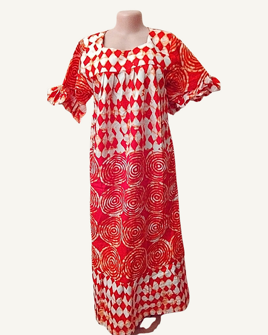Robe longue batik africain rouge et blanc, motifs losanges en haut et spirales concentriques en bas, encolure carrée avec plissés, manches courtes à volant froncé, coupe droite maxi.