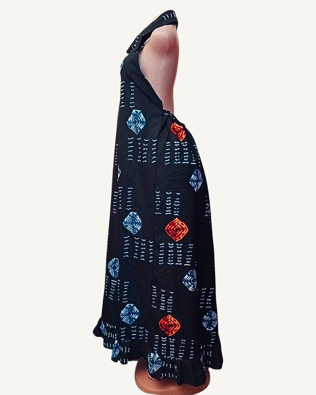 Vue de profil — robe longue adire africain noir, col chemise halter, motifs losanges concentriques bleu et rouge orangé alternés avec tirets blancs, silhouette droite et fluide jusqu'à la cheville, volant froncé en ourlet.