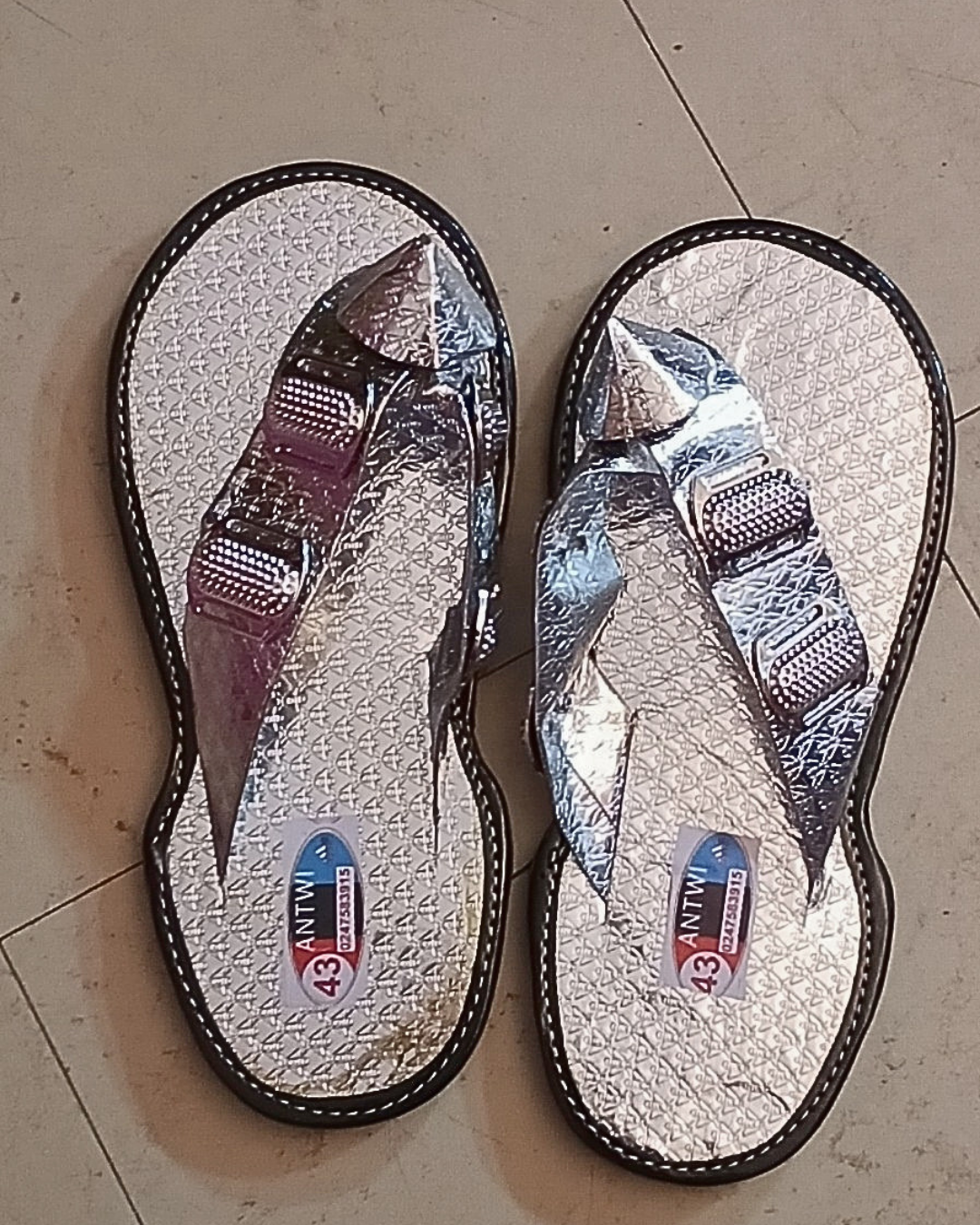 Agbodje argentées traditionnelles ivoiriennes portées · bride en V métallisée argent · médaillon argenté · semelle gaufrée argent · contour noir · vue de dessus.