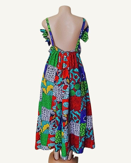 Dos entièrement nu d'une robe wax patchwork multicolore, bretelles larges à volants, buste élastiqué, coupe évasée et généreuse longueur maxi.