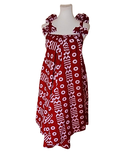 Robe batik bordeaux et blanc à motifs géométriques africains, buste froncé, bretelles larges nouées aux épaules, ourlet asymétrique, coupe évasée.